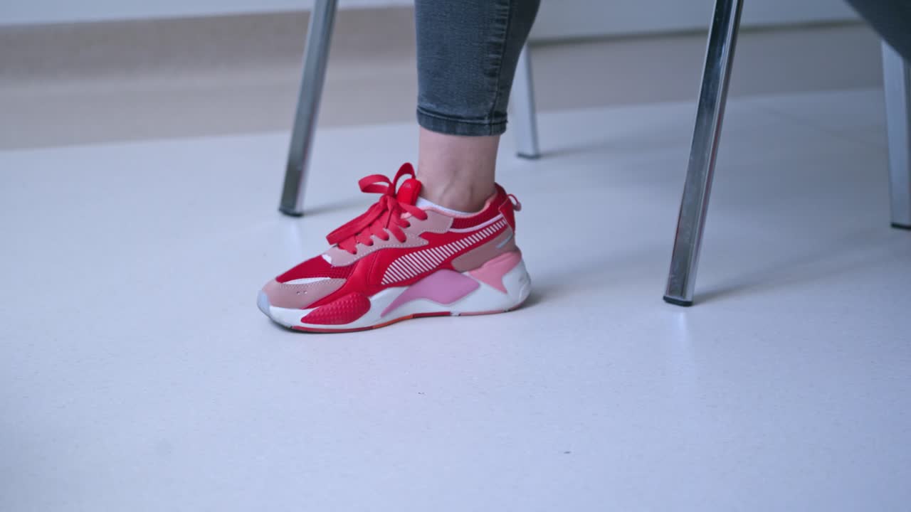 Woman tying shoelace indoor. Close up view of woman hands tying shoelaces on sneakers