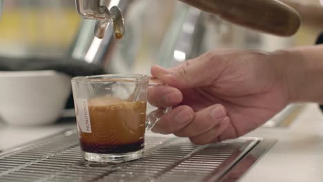 la mano se extiende para agarrar una taza fresca de café como los últimos gotas de líquido marrón caen