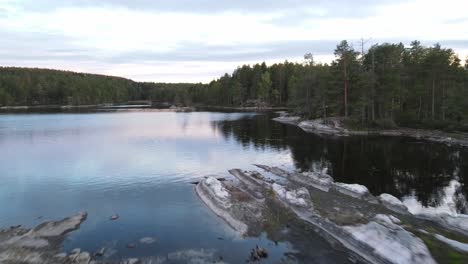 aerial view flying through trees on a small rocky island surrounded by water