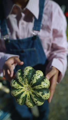 person holding a small striped pumpkin