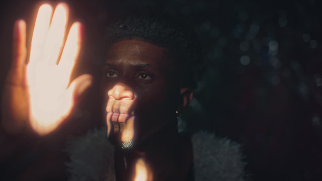 African American Man Looking Upward at Harsh Light Beam in Dark Room