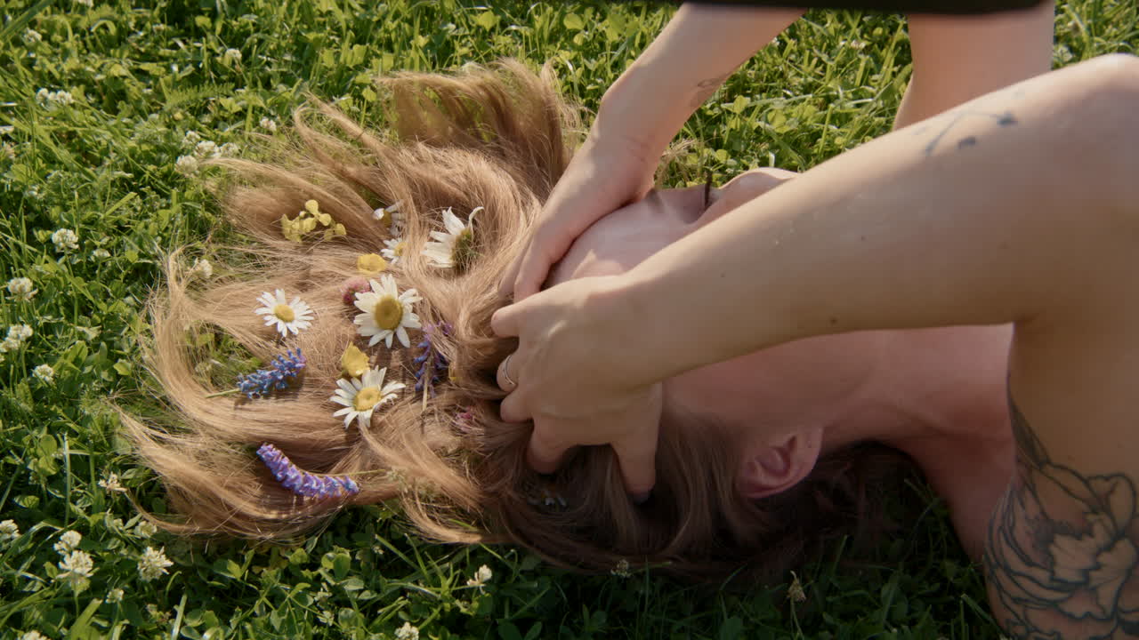 Woman with flowers in her hair lying on grass