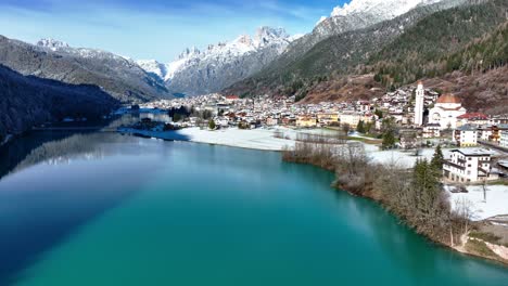 drone aerial view of mountains, lake and small town with snow in winter in europe