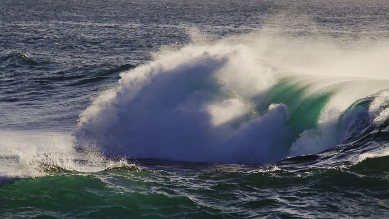 Slow motion wave crashing as ocean spray mist rises off top, natural backdrop background