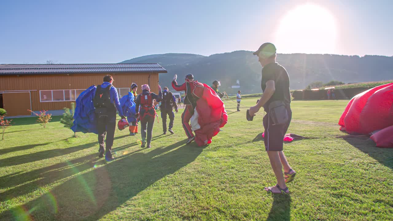Group Of Skydivers Carrying Parachutes High Five To Celebrate A Successful Jump