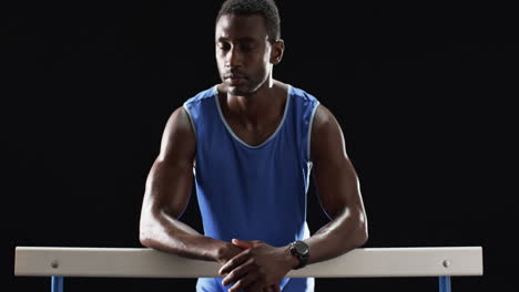 african american athlete resting on the hurdles on a black background