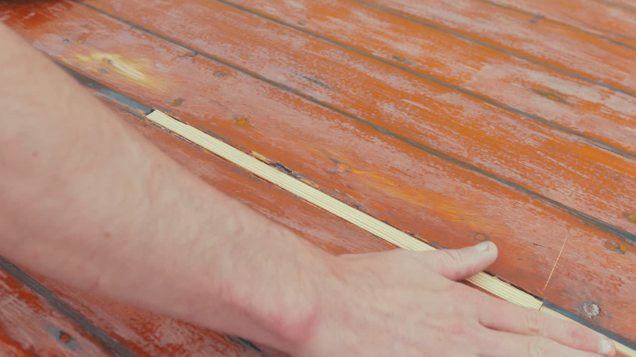 보트 조타실 선실 지붕의 샌딩 처리된 나무 인서트를 손으로 문지름