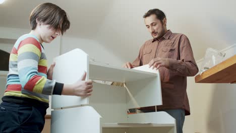 father and son assemble new furniture purchased online. importance of transfer of experience and training. family business and saving the family budget