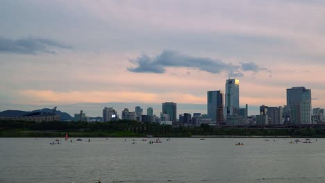 Panorama-De-La-Metrópolis-De-Seúl-Con-Turistas-Disfrutando-De-La-Actividad-De-Deportes-Acuáticos-En-El-Río-Han,-Distrito-De-Gangnam,-Corea-Del-Sur