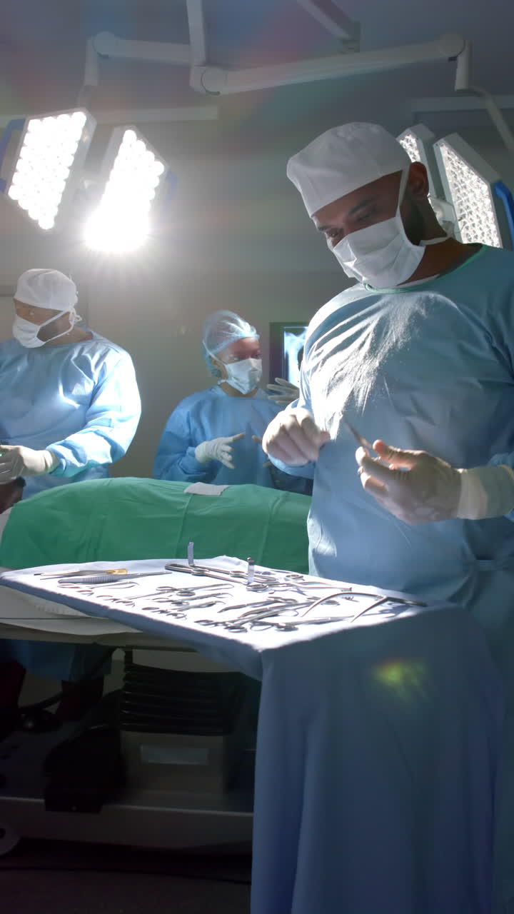 Vertical video of african american male surgeon preparing surgical instruments, slow motion