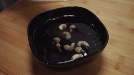 Cacahuetes-Cayendo-En-Un-Recipiente-Negro-Con-Agua-Para-Remojar