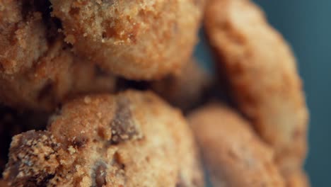 a vertical macro close up cinematic shot of a plate full of crispy chocolate chip cookies, on a 360 rotating stand, studio lighting, super slow motion, 120 fps, full hd video