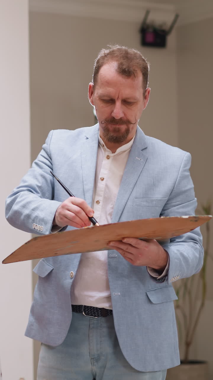 el artista mezcla los colores con el pincel en la paleta. el pintor hábil comienza a pintar a una mujer joven con la elección de colores en un estudio bien iluminado. obra de arte del maestro