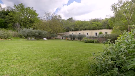 in the backdrop, a picturesque stone house stands proudly, surrounded by a lush green lawn dotted with majestic trees