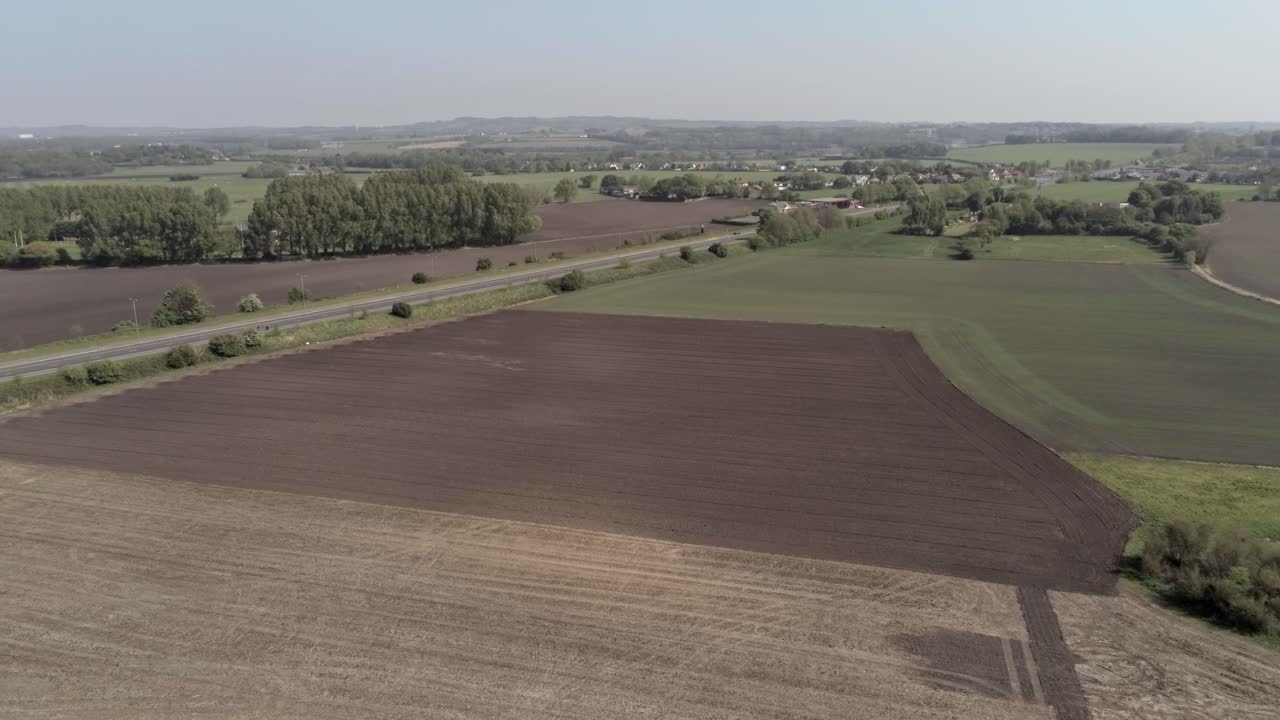 Widok z drona wznoszący się w lewo nad brytyjską autostradą A580 East Lancs na wiejskich terenach rolniczych.