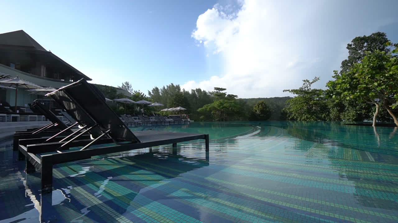 Two empty beach recliners sit in the shallow end of a resort pool