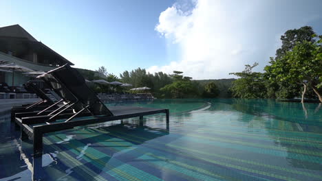 two empty beach recliners sit in the shallow end of a resort pool