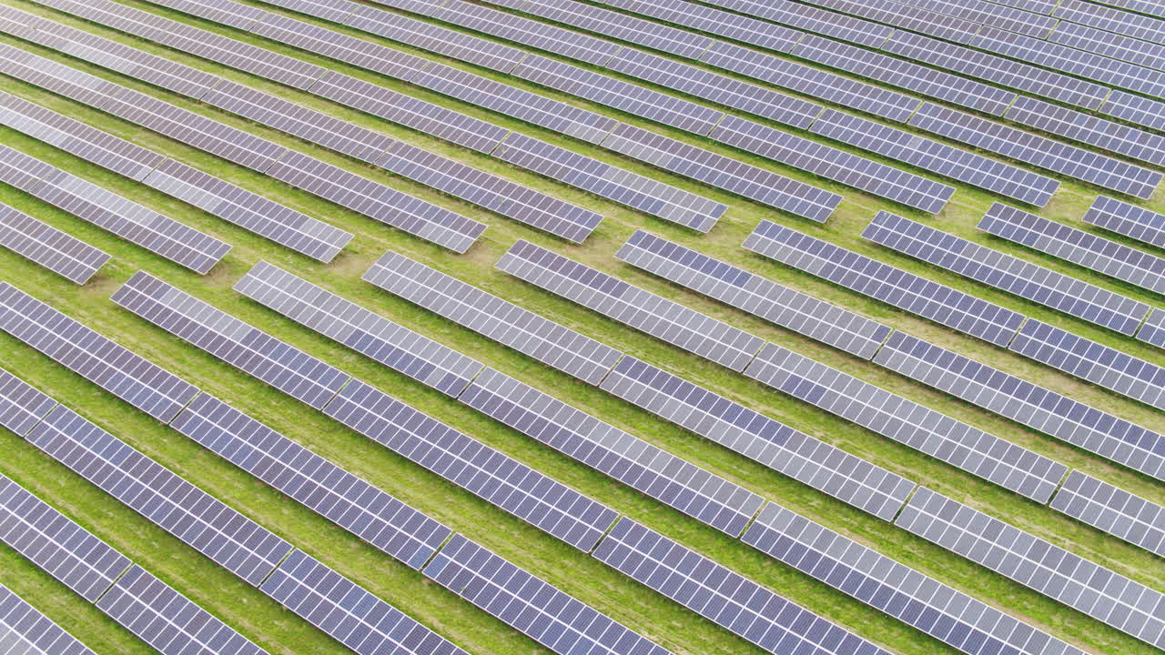 Huge endless solar panel array in a flat english field, aerial footage on a sunny day