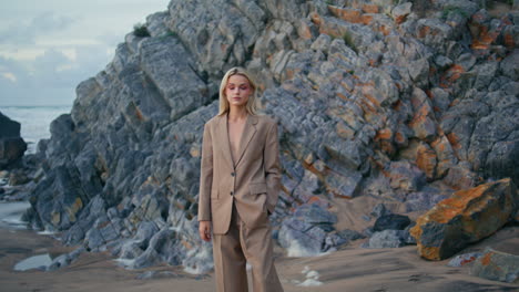 gorgeous lady posing rocky beach on evening. sexy fashion model in suit stepping