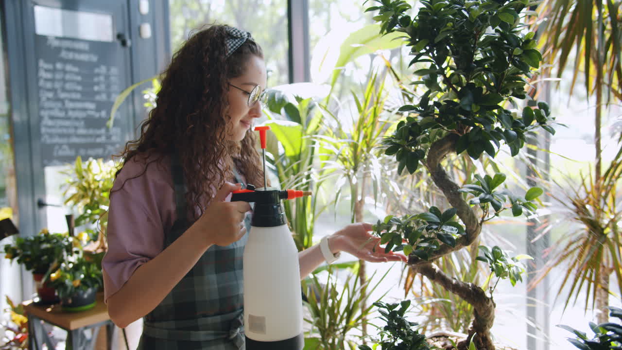 Woman Watering Bonsai Plants in a Flower Shop