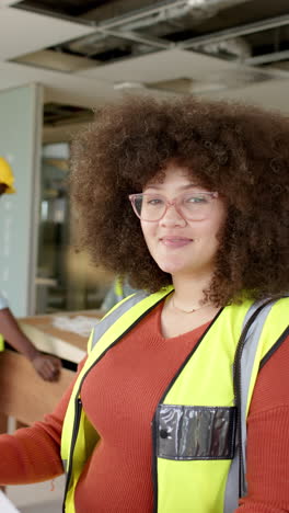 vertical video of casual biracial female architect looking at plans, slow motion, copy space
