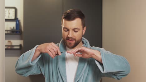 a well-groomed young man cuts his fingernails