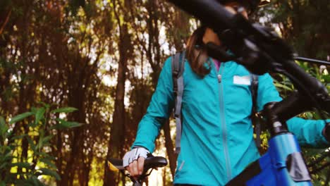 female mountain biker walking with bike