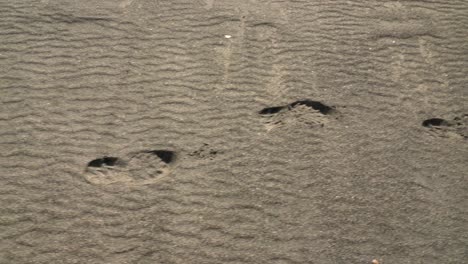 close up panning shot of footprints on white sandy beach at sandur on sandoy during sunny day