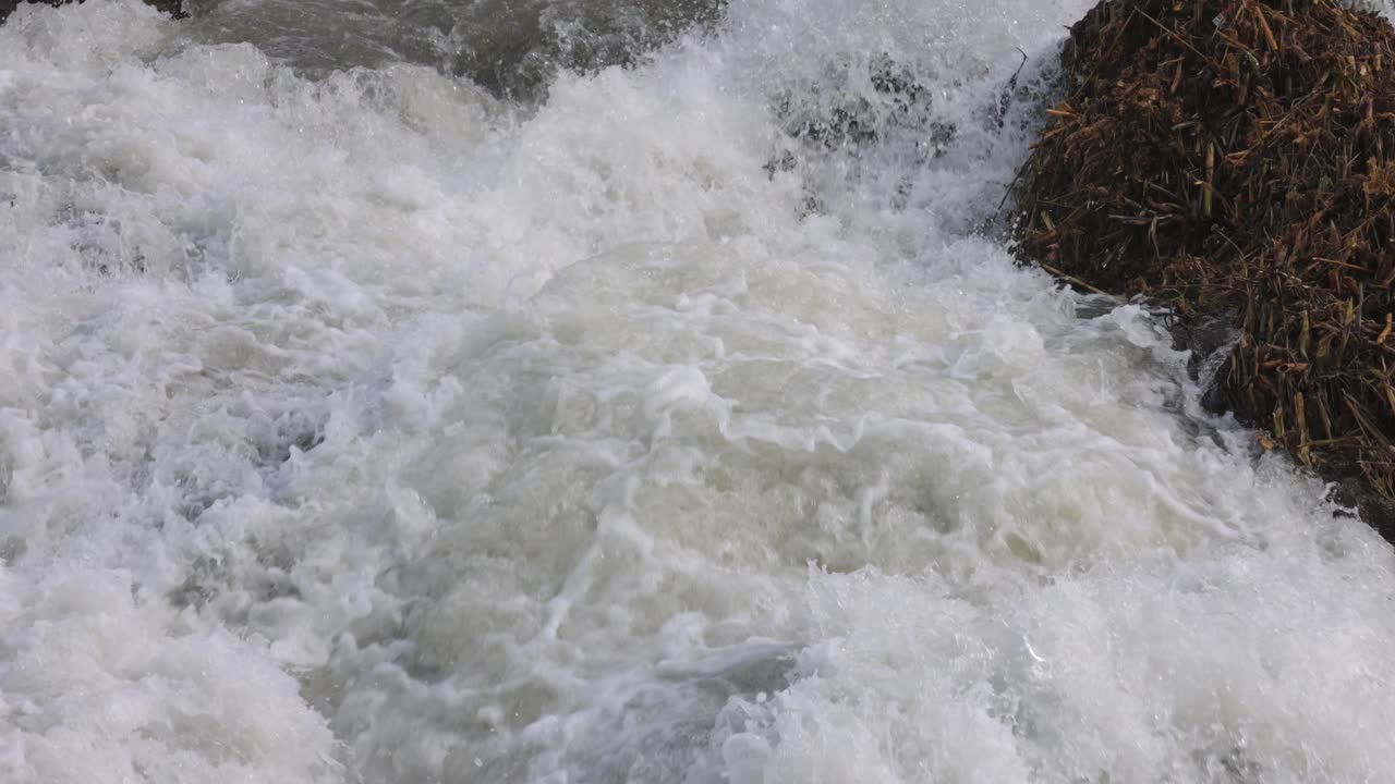 Nahaufnahme von schnell fließenden Wildwasser-Stromschnellen in Cornwall, England, die turbulente Süßwasserbewegung, spritzenden Schaum, natürliche Energie und rohe Flusskraft in einer Naturkulisse zeigen.