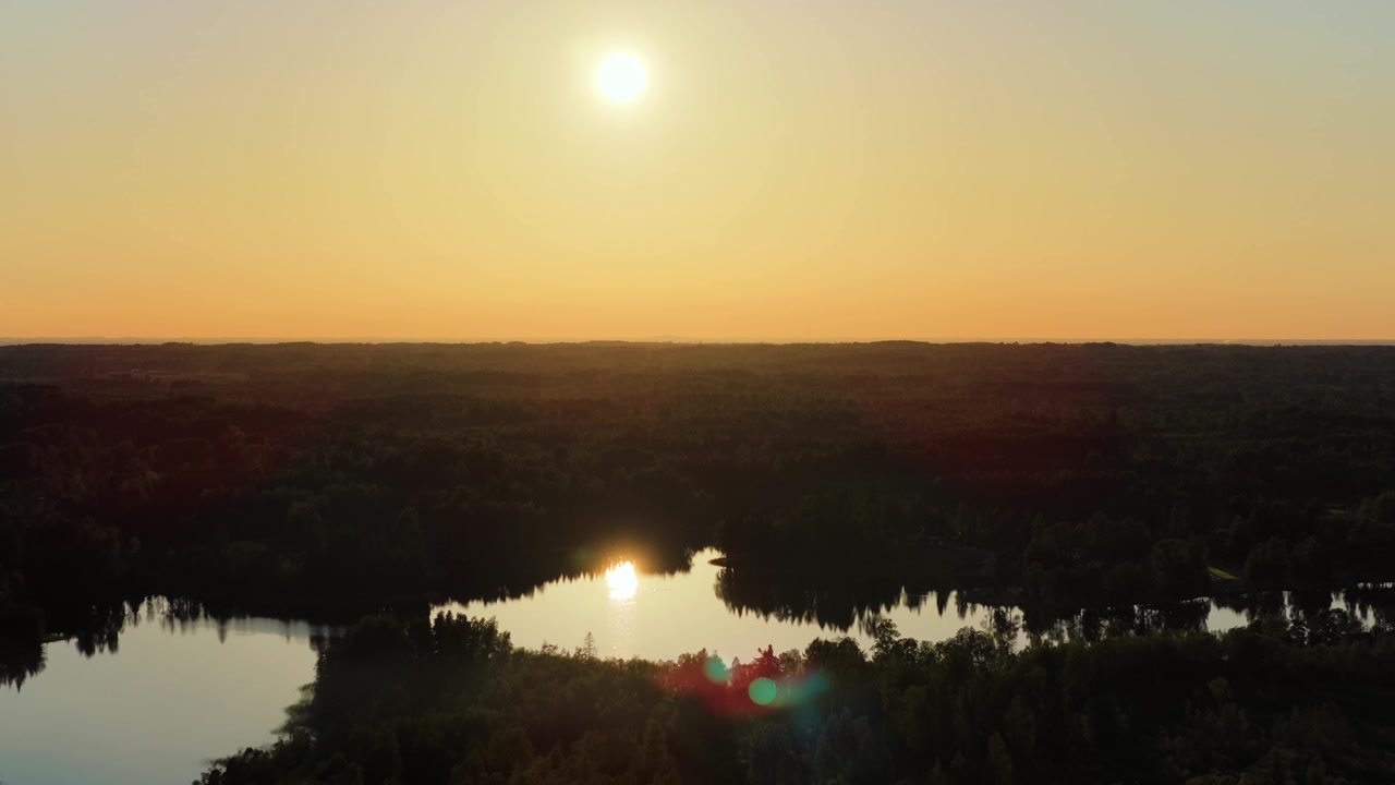 Aerial view of a serene lake reflecting the bright sun during a beautiful summer sunset