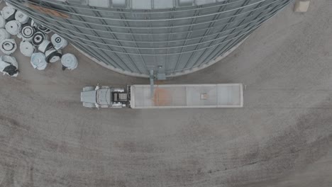 drone footage of trucks semi loading corn at farmstead grain bin.