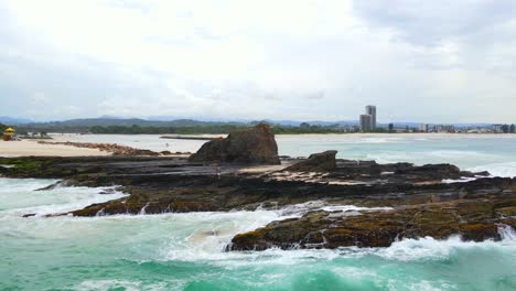 powerful waves hitting currumbin rock formation near sandy beach - currumbin beach, qld, australia