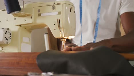 hands of african american craftsman sewing leather in leather workshop