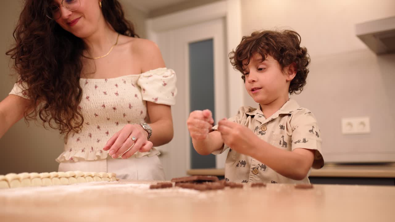 Happy boy breaking chocolate in kitchen at home