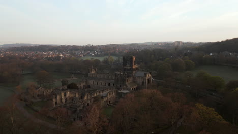 aerial zoom shot of kirkstall abbey at dawn on spring morning with birds flying around tower