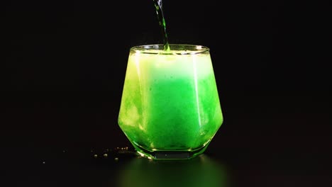 green drink poured into glass, creating foam