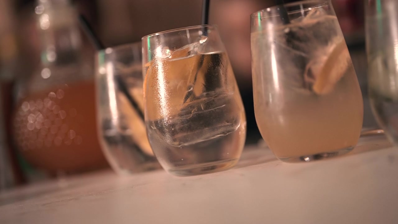 Close-up of cocktails with citrus slices and straws on a bar counter. Ideal for hospitality marketing or social media content.