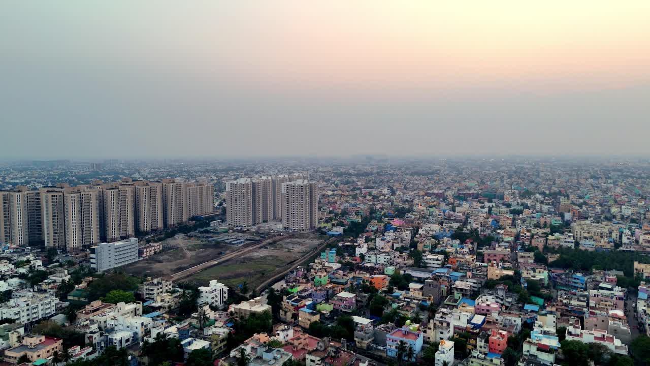 High-angle drone footage of Chennai during an early morning sunrise. New apartment towers rise above a sea of traditional buildings. Perfect for themes of urban expansion and population density
