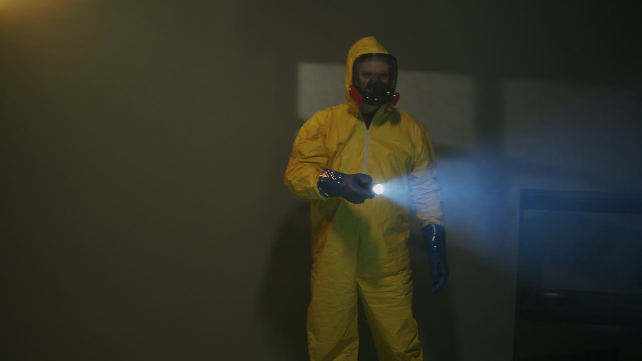hombre vestido con traje hazmat explora una habitación oscura
