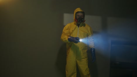 hazmat suit wearing man explores a dark room