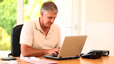 hombre escribiendo algo en su computadora portátil y posando