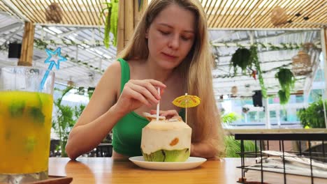 woman enjoying a coconut drink at a tropical cafe