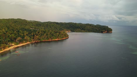 Aerial-drone-shot-of-peaceful-island-coast-and-lagoon-with-calm-sea-waters-and-lush-tropical-jungles