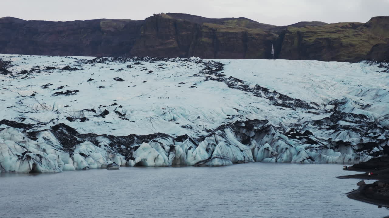 Tourists appears tiny against the vast, rugged expanse of a massive glacier