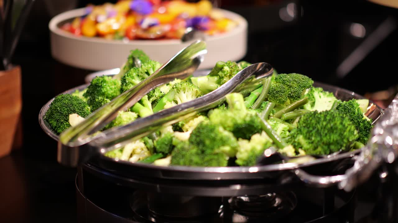 Steamed broccoli in a bowl at a buffet or catering event, fresh and ready to serve.