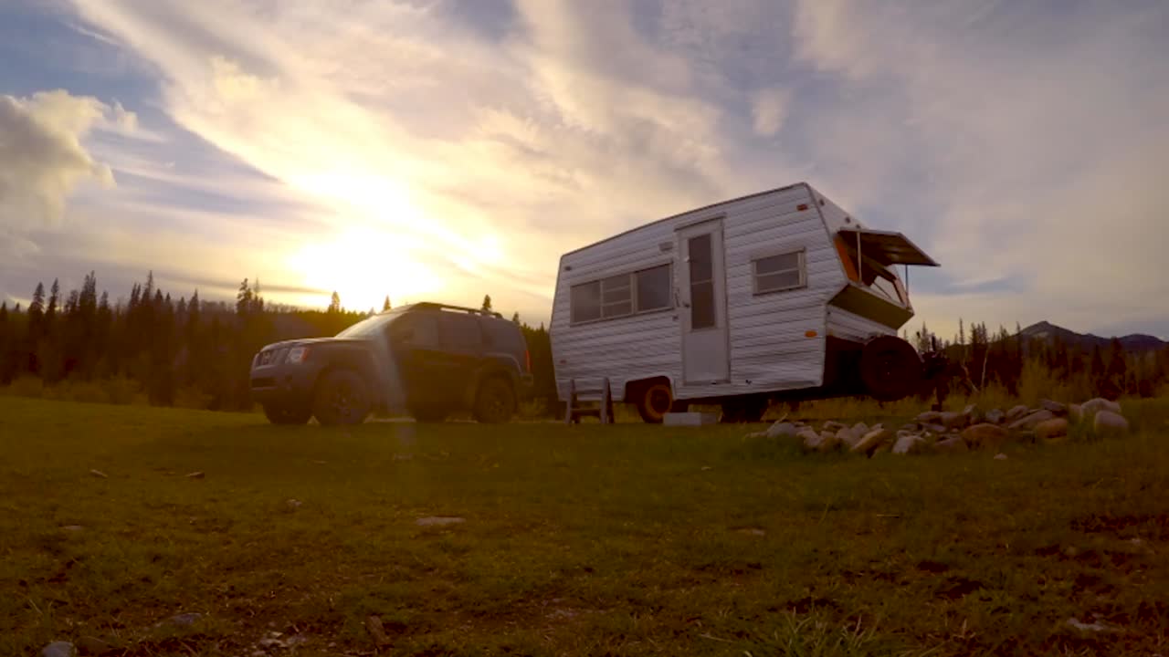 An SUV and old vintage trailer at a campsite. Late afternoon time lapse