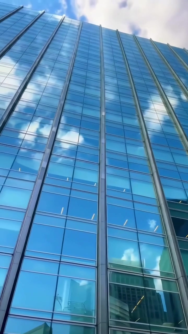 Vista de Baixo Ângulo de um Arranha-Céu Moderno de Vidro Refletindo Nuvens