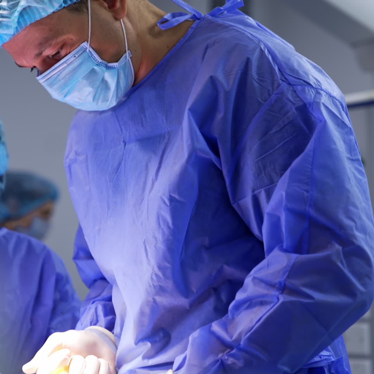 Doctor in protective uniform and mask giving a shot to a patient. Medical staff walking at backdrop