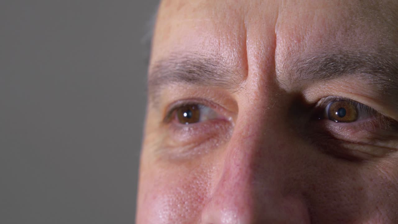 Close Up of Man's Eyes Acknowledging with Hidden Smile Looking into a Bright Light