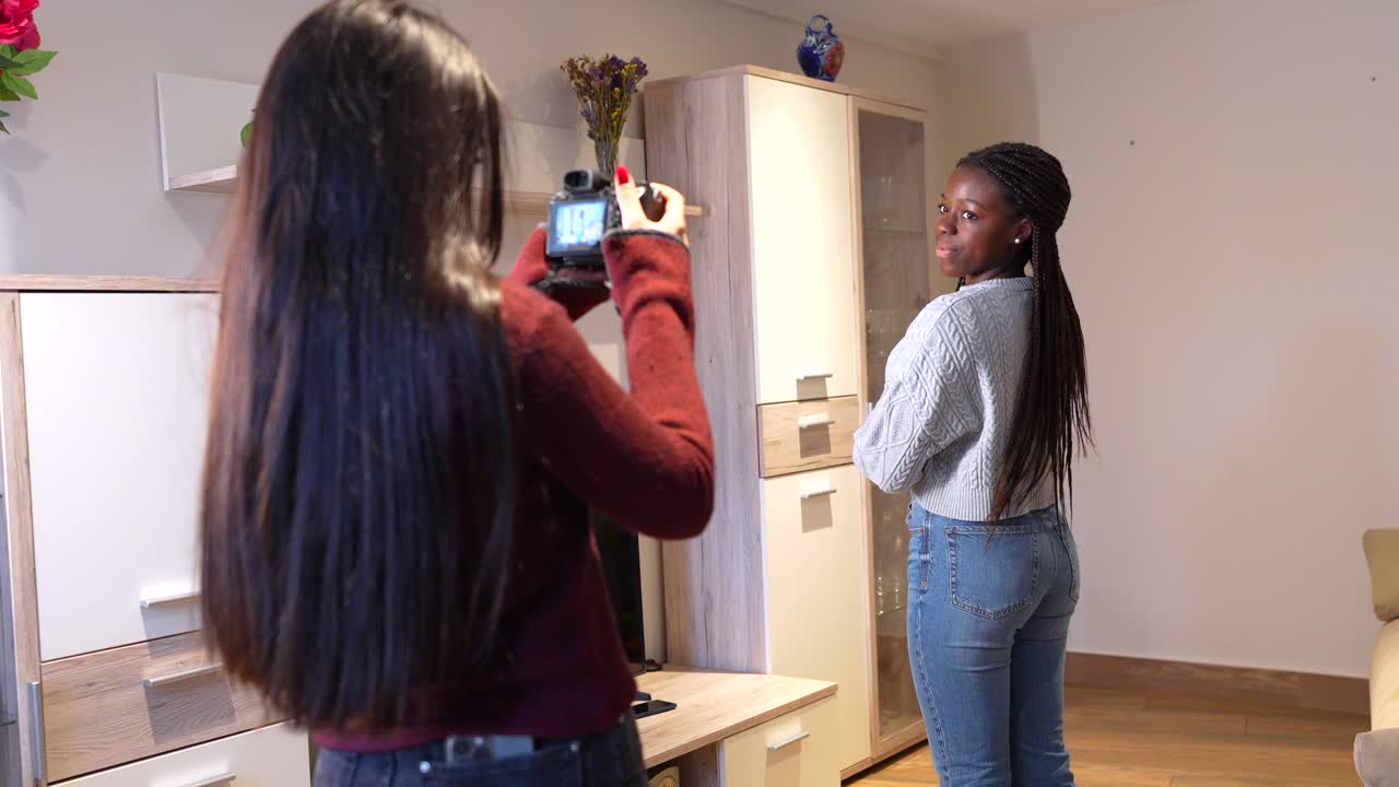 Woman taking photos of another woman indoors